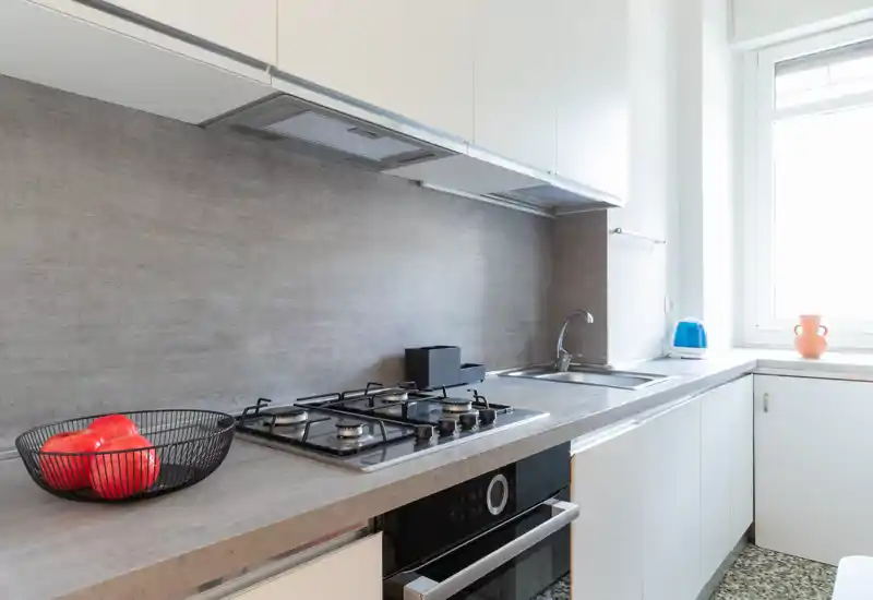 Bright modern kitchen with a built-in gas hob, stainless sink and clean countertops; natural light from a window and minimal decorative touches create a fresh, functional space.