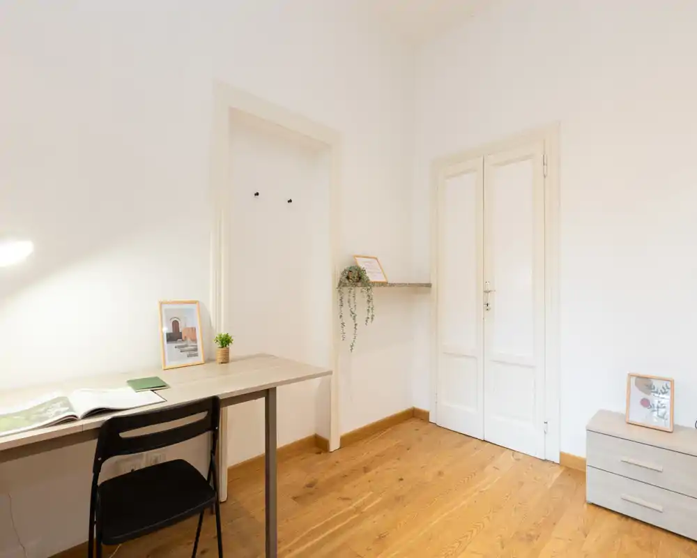 Bright, minimal living area with a tidy desk, chair and light wood floor — a calm, functional space ideal for work and relaxation.