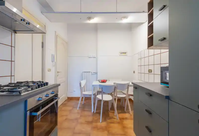 Bright, modern kitchen with a gas stove, built-in oven, cabinets and a small dining table with chairs — a practical and well‑lit space for everyday meals.