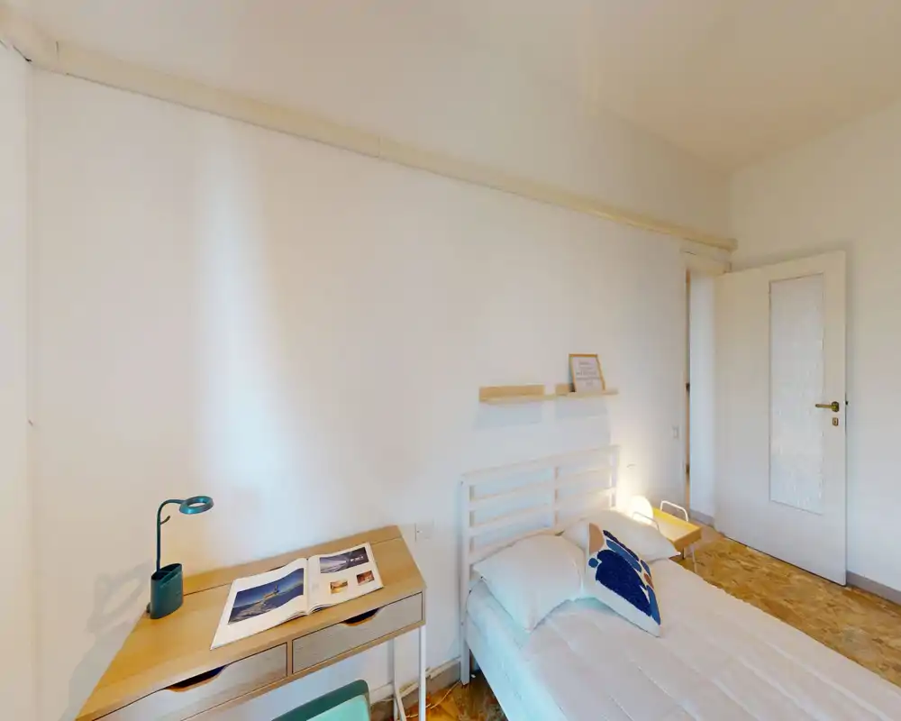 Dormitorio luminoso y de estilo sencillo con cama individual, mesita y un pequeño escritorio: líneas limpias y luz natural que crean un ambiente tranquilo.