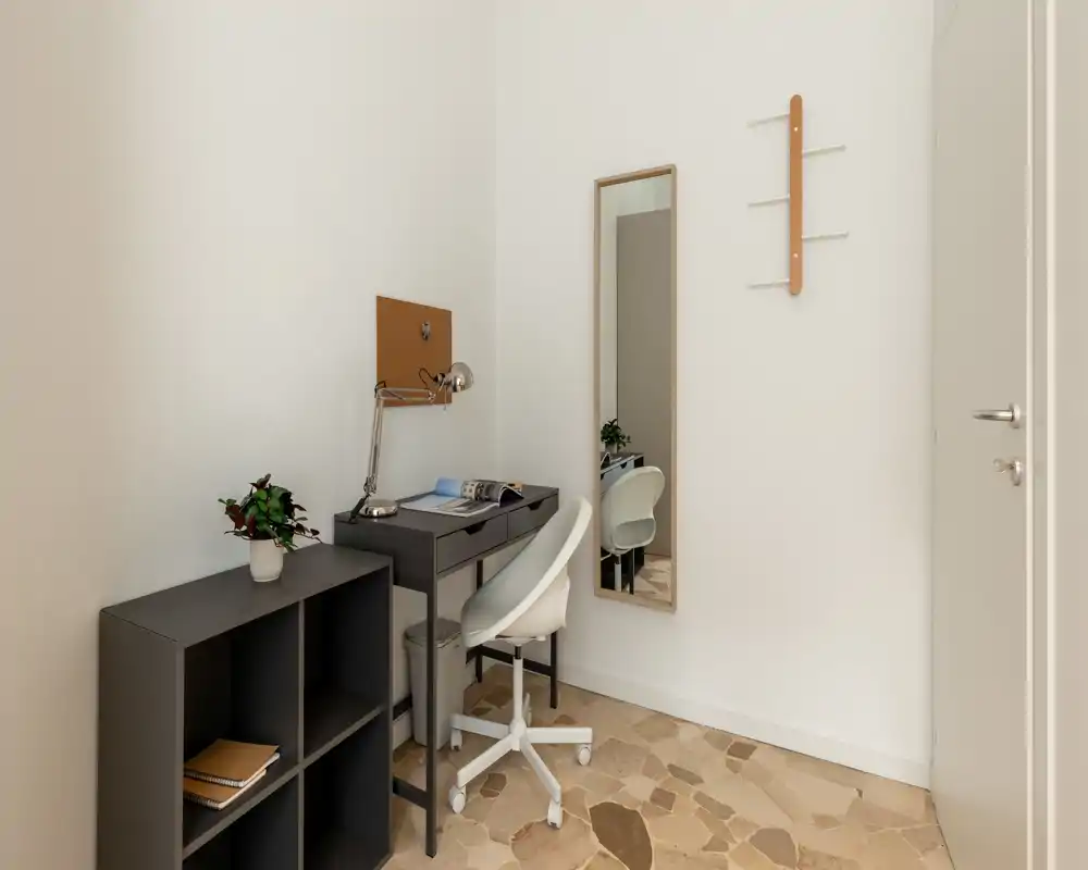 Rincón de oficina en casa compacto en tonos neutros con escritorio pequeño, silla giratoria, espejo y estantería—ideal para trabajar en un apartamento minimalista.