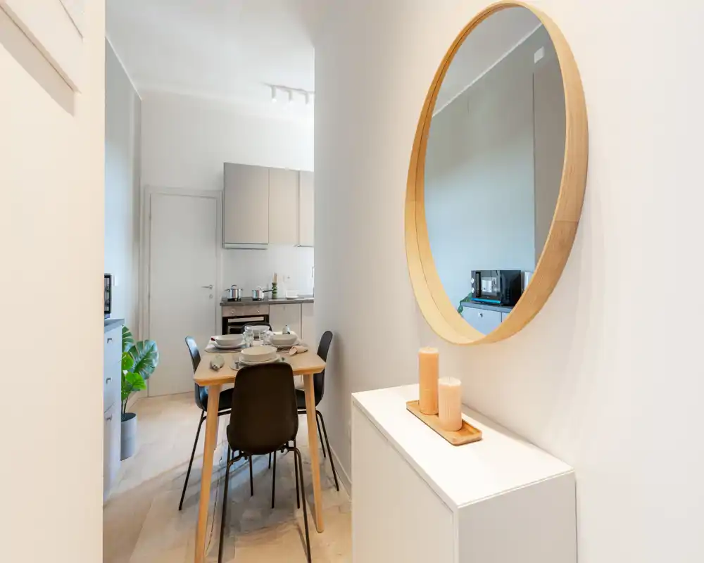 Accogliente angolo pranzo moderno e luminoso con tavolo in legno e sedie nere vicino a una cucina aperta — ben curato per i pasti.