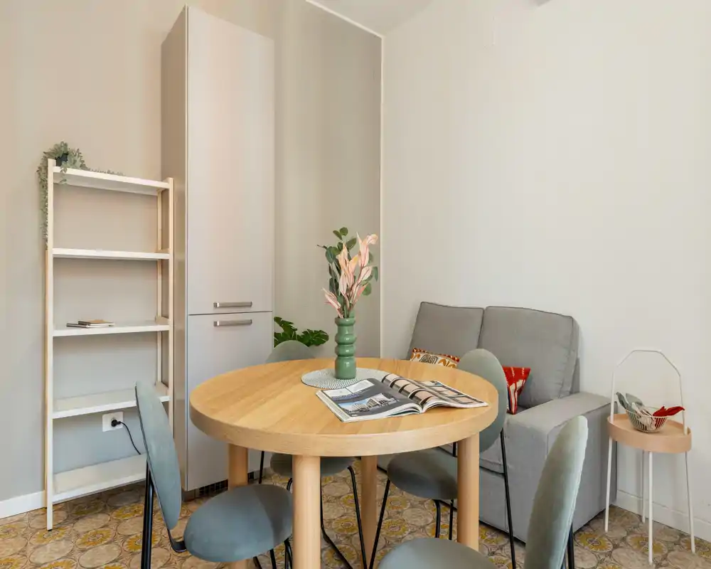 Coin repas chaleureux avec table ronde en bois, chaises rembourrées et vase décoratif—idéal pour petits repas et réunions informelles.