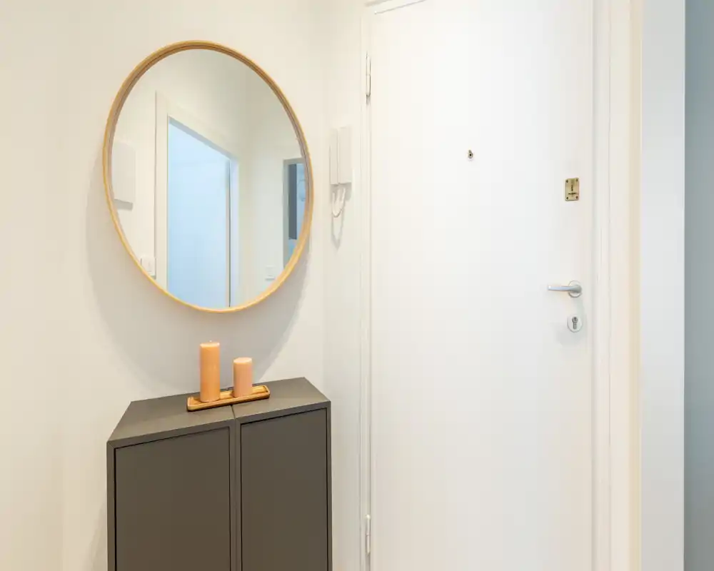 Entrée minimaliste avec console moderne, miroir rond au mur et bougies décoratives — lumineuse et accueillante.