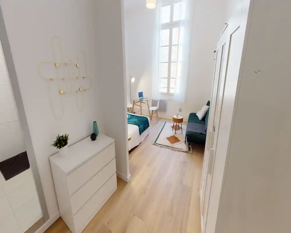 Chambre moderne et lumineuse avec lit complet, grande fenêtre apportant une belle lumière naturelle, un petit espace de travail et un coin détente confortable — idéale pour une personne seule ou un couple.