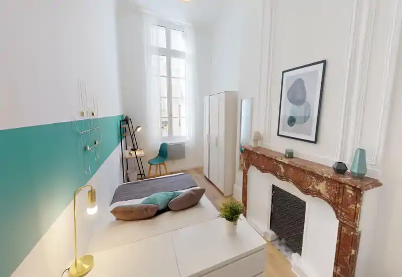 Chambre lumineuse et élégante avec lit double, textiles douillets et grande fenêtre apportant une belle lumière naturelle. Décoration soignée et petit coin bureau pour un séjour confortable.