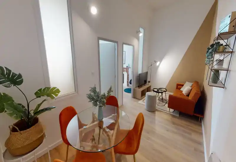 Espace de vie moderne et lumineux avec un canapé couleur rouille, un coin TV et une table à manger en verre avec chaises orange — décoré avec goût et accueillant.