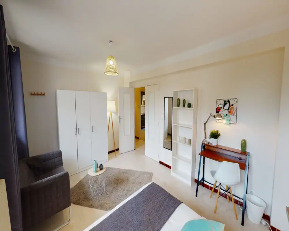 Spacious, well-lit bedroom with a double bed, cozy rug and a small seating area. Includes wardrobe, shelving and a compact desk ideal for remote work.