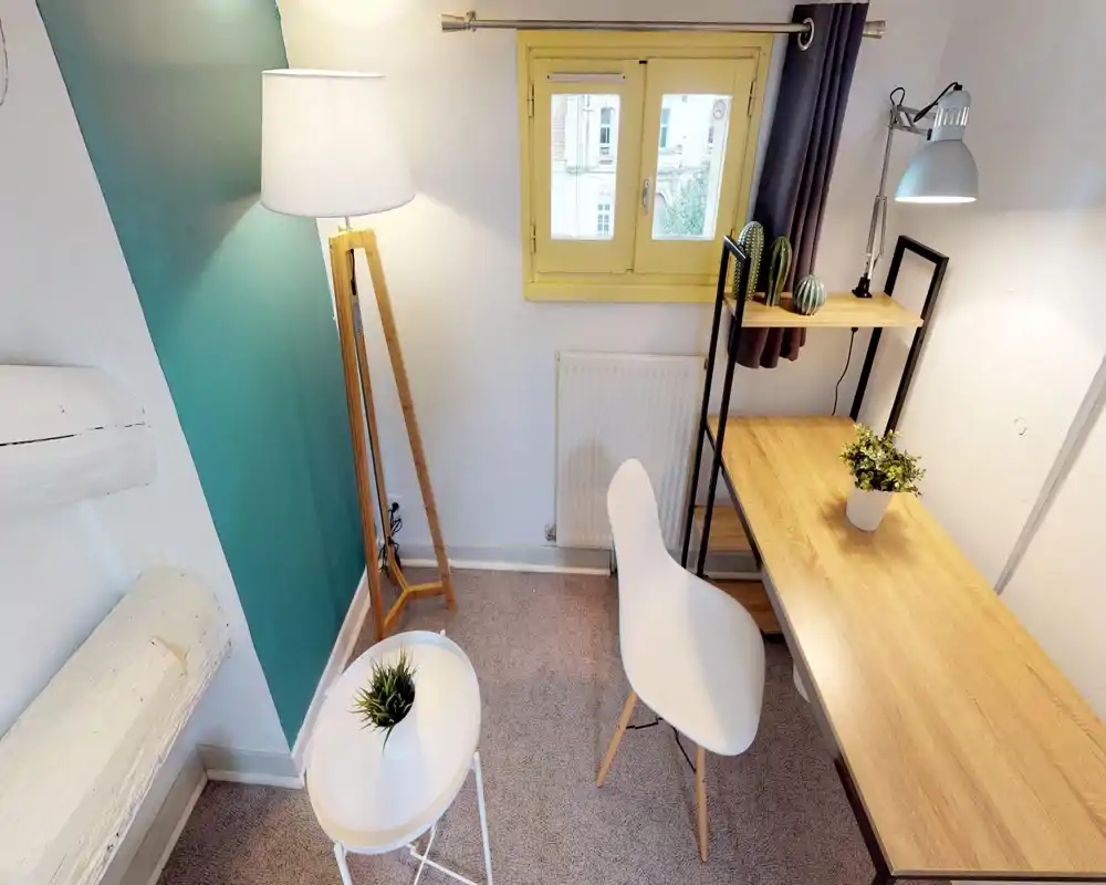 Compact, well-lit workspace corner with a wooden desk, modern white chair, floor lamp and small decorative plants — ideal for focused study or remote work.