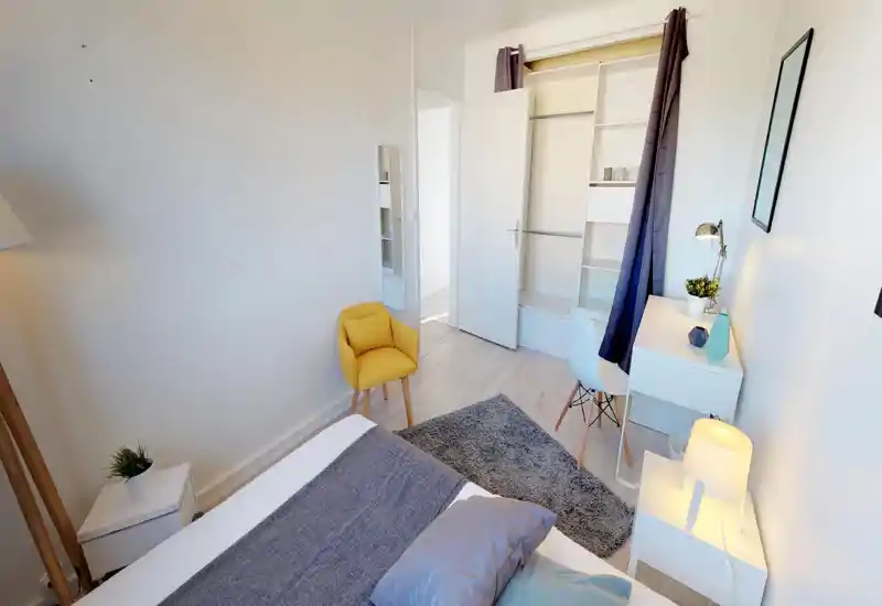 Bright, well-styled bedroom with a visible double bed, soft textiles, a bedside lamp and a small desk — comfortable and neatly arranged for rental photos.