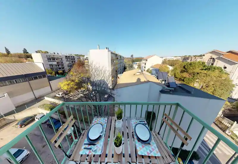 Vue depuis un balcon sur une rue résidentielle ; l'image est fortement déformée mais montre une balustrade extérieure et des bâtiments à distance.