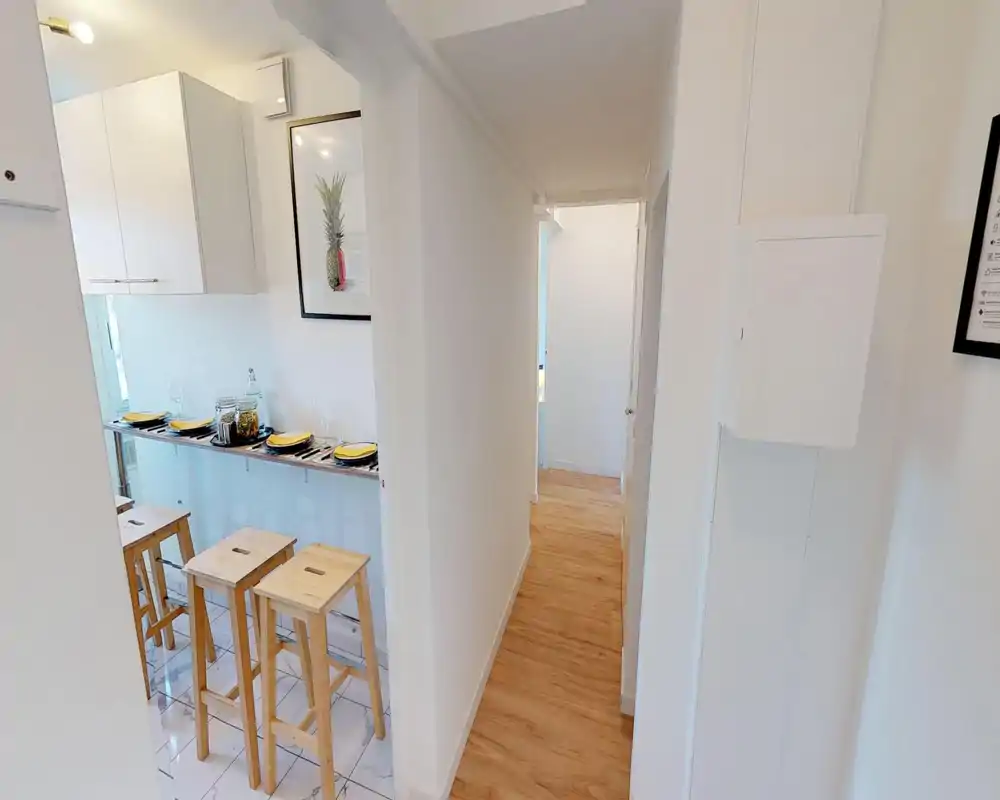 Cucina compatta e luminosa con bancone per la colazione e sgabelli in legno; piatti apparecchiati e decorazioni che rendono l'ambiente accogliente e moderno.