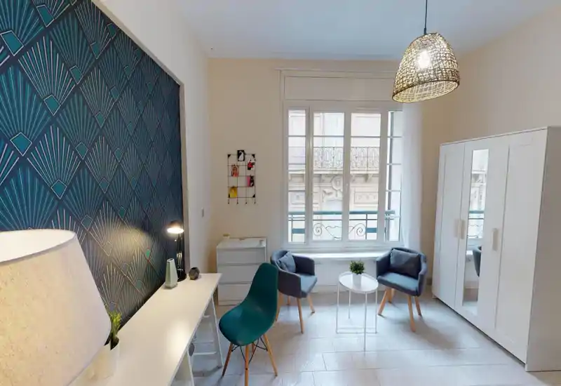 Bright, stylish bedroom corner with patterned feature wall, seating area, wardrobe and large window providing abundant natural light.