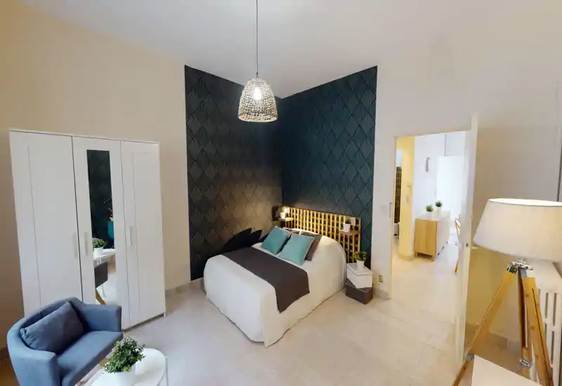 Bright, stylish bedroom featuring a double bed against patterned accent wallpaper, bedside plants and modern pendant lighting — cozy and well staged for rental photos.