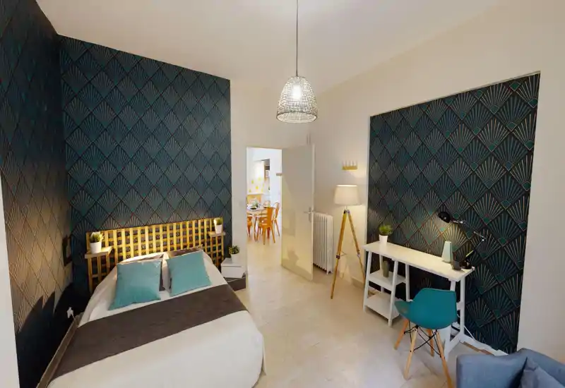 Bright, stylish bedroom with a double bed, patterned feature walls and a small desk — ideal for a comfortable stay or working from home.