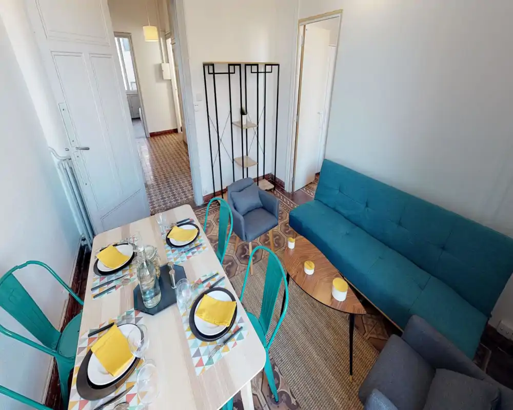 Bright, stylish living room with a teal sofa, armchairs and a set dining table — an inviting open space ideal for socializing and meals.