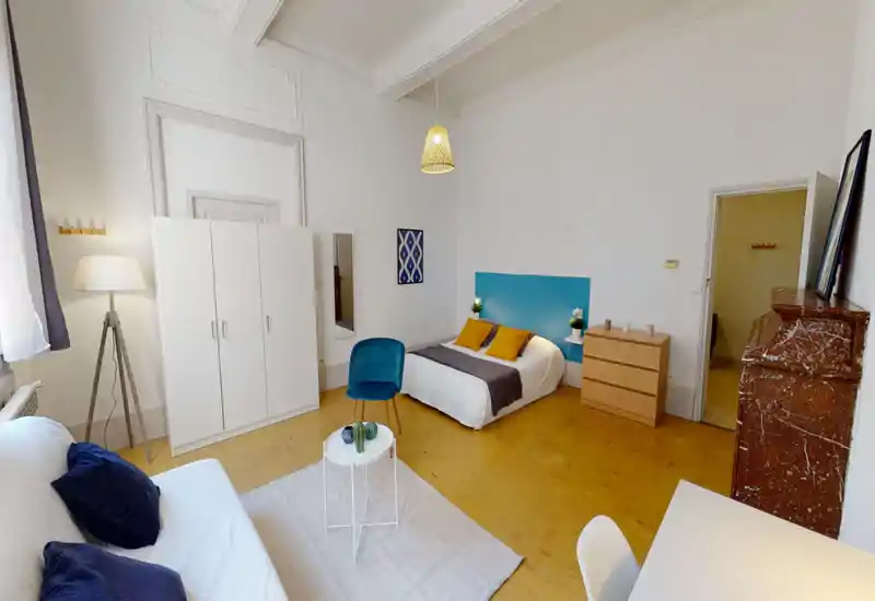 Camera da letto ampia e luminosa con letto matrimoniale basso, testiera turchese, tessili accoglienti e arredi moderni, perfetta per un soggiorno confortevole.