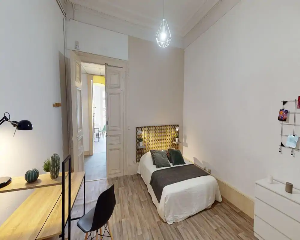 Bright, well-staged bedroom with a double bed, decorative headboard lighting and a small desk by the wall — cozy and contemporary feel, ideal for a rental listing.