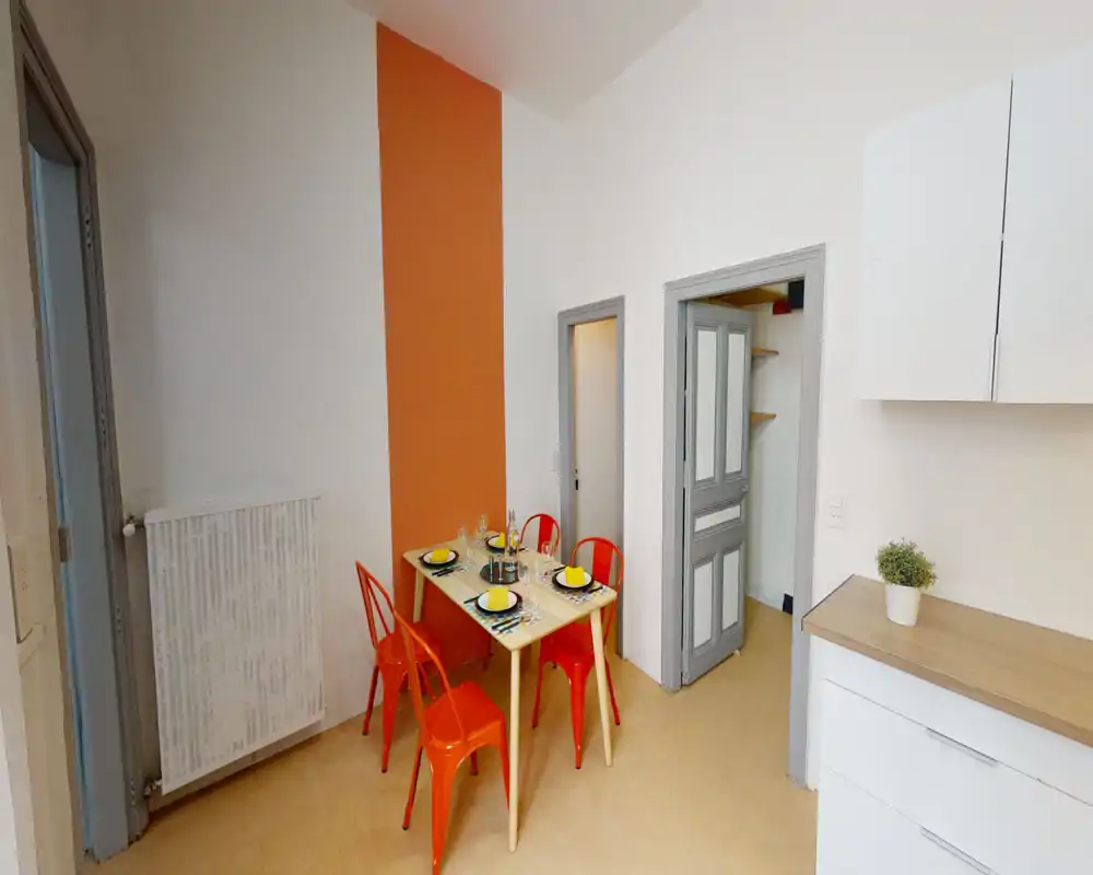 Coin repas lumineux et compact avec une table pour quatre, mur d'accent orange et chaises métalliques assorties pour une ambiance gaie.