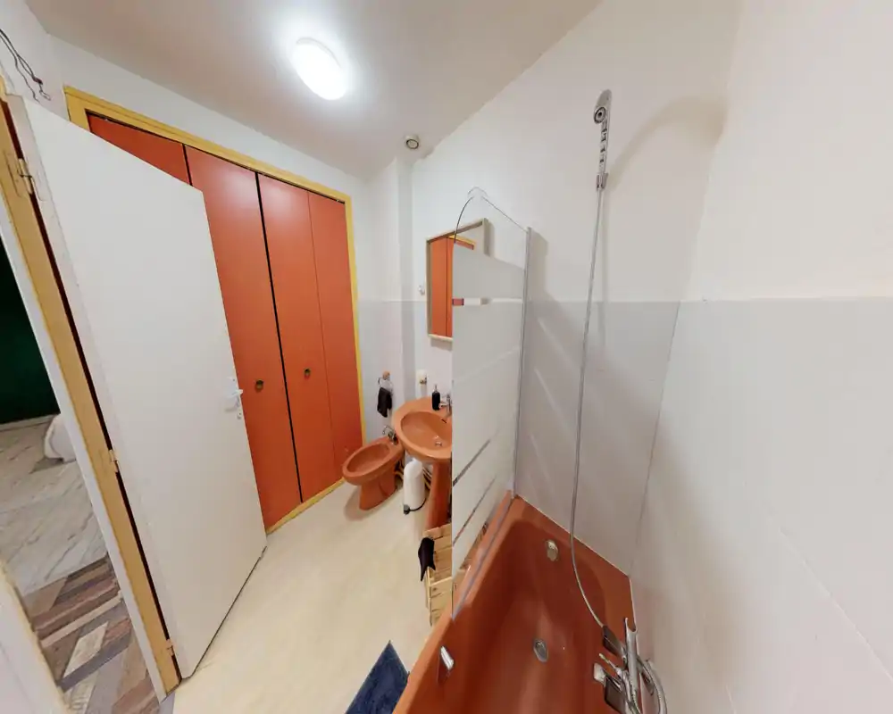 Salle de bains lumineuse avec baignoire, douche, lavabo et bidet en finition terre cuite coordonnée ; carreaux blancs et meuble miroir complètent l'espace.