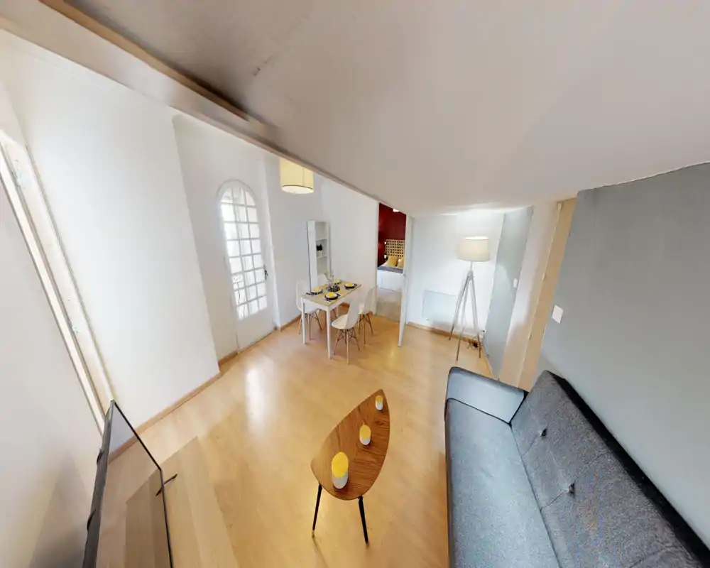 Espace de vie lumineux et moderne avec canapé confortable, table basse et coin repas. La configuration ouverte et la décoration soignée rendent la pièce accueillante et propice aux échanges.