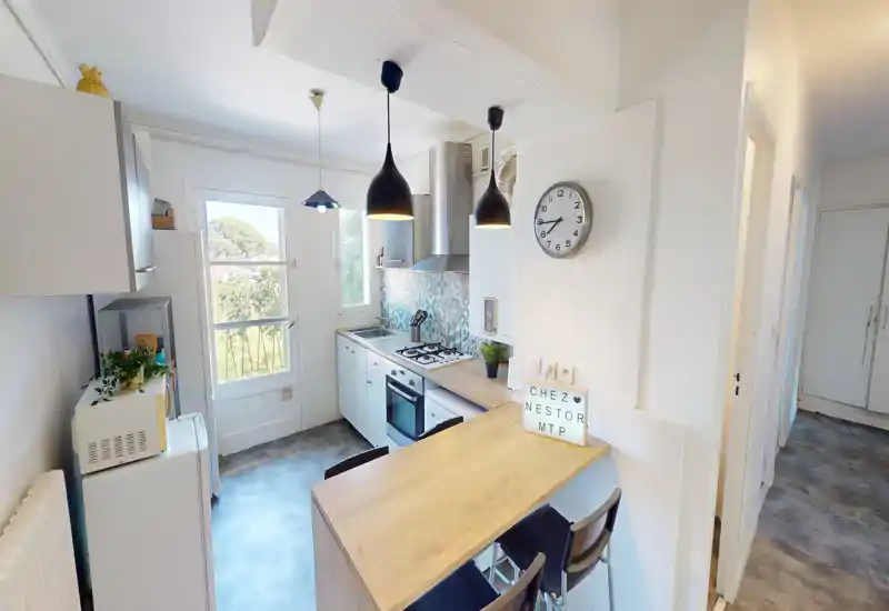 Bright, compact kitchen with a wooden breakfast bar, pendant lighting, tiled backsplash and built-in oven—ideal for a practical, stylish rental.