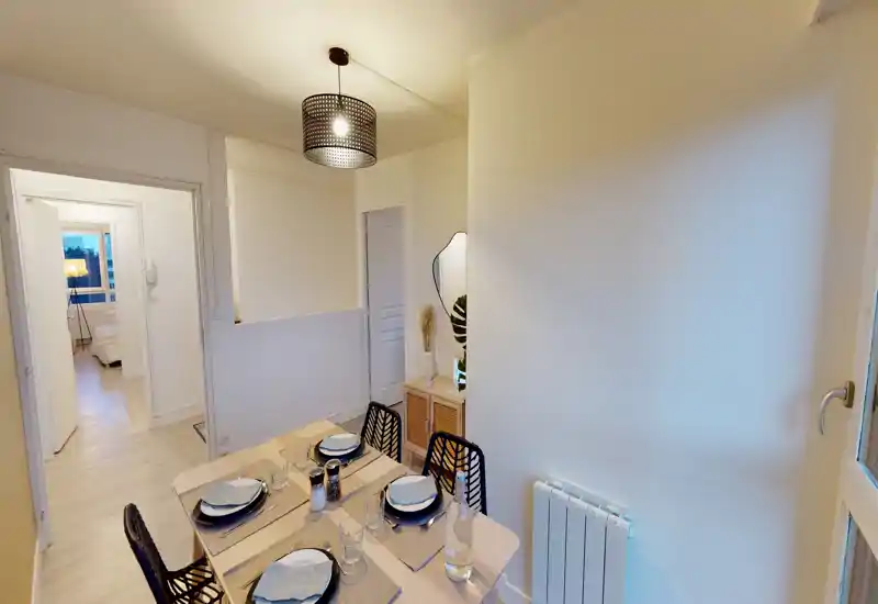 Coin repas lumineux et élégant pour quatre personnes, table en bois, chaises modernes et suspension douce — idéal pour des repas conviviaux.
