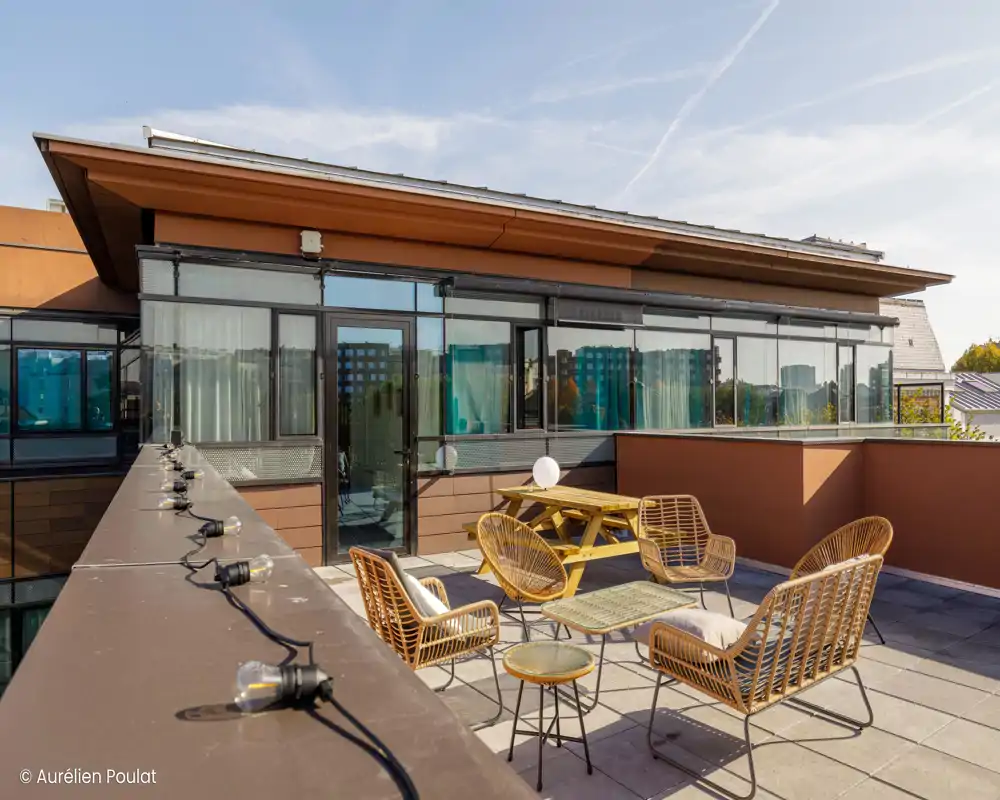 Terrasse sur le toit ensoleillée avec plusieurs chaises d'extérieur et une pergola ombragée, parfaite pour se détendre ou recevoir en plein air.