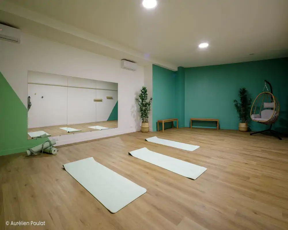 Grand espace de vie au mobilier minimaliste avec sol en bois, éclairage encastré au plafond et banquettes basses le long des murs ; la pièce est ouverte et polyvalente.