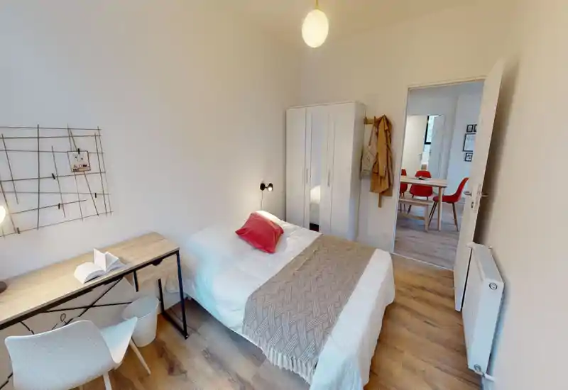 Bright, modern single bedroom with a neatly made bed, wooden desk and wardrobe; warm textiles and simple decor create a cozy, well-staged space ideal for rental photos.