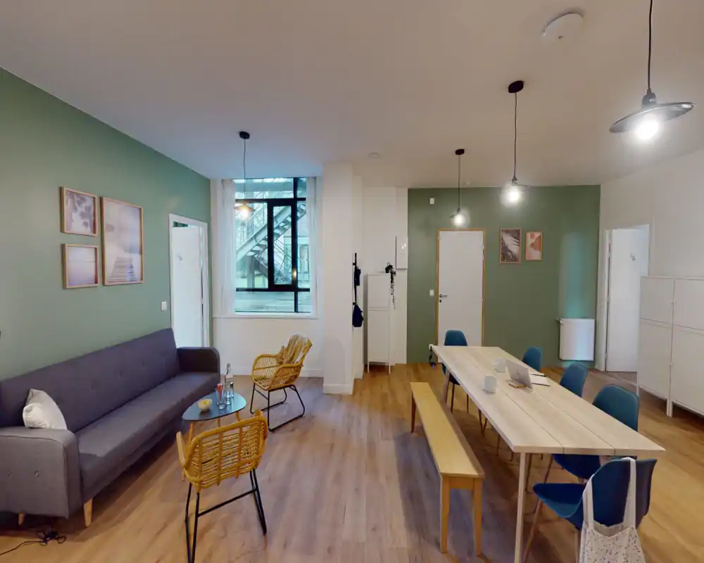 Amplia sala de estar bien equipada con un sofá largo, sillas de mimbre y una gran mesa para comer/trabajar; luz natural y suelo de madera cálido que crean un espacio acogedor y versátil.