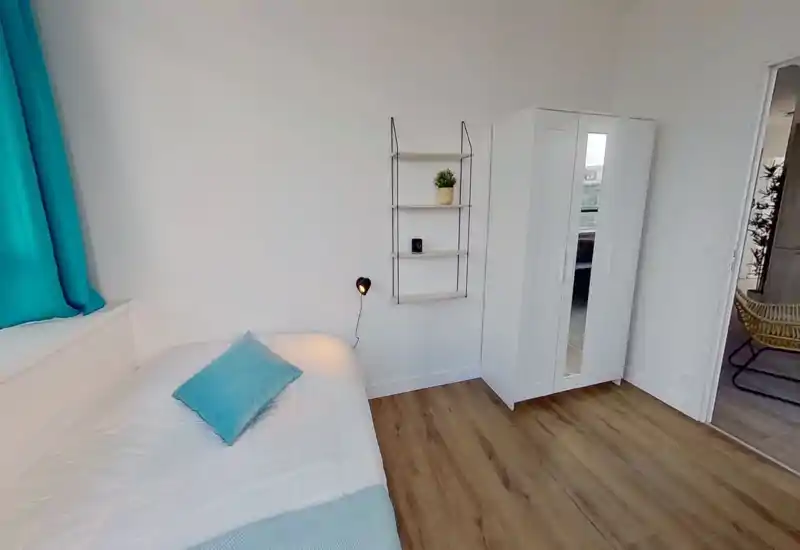 Dormitorio luminoso y de diseño sencillo: cama blanca con acentos turquesa, armario blanco y suelo de madera, ambiente moderno y acogedor.