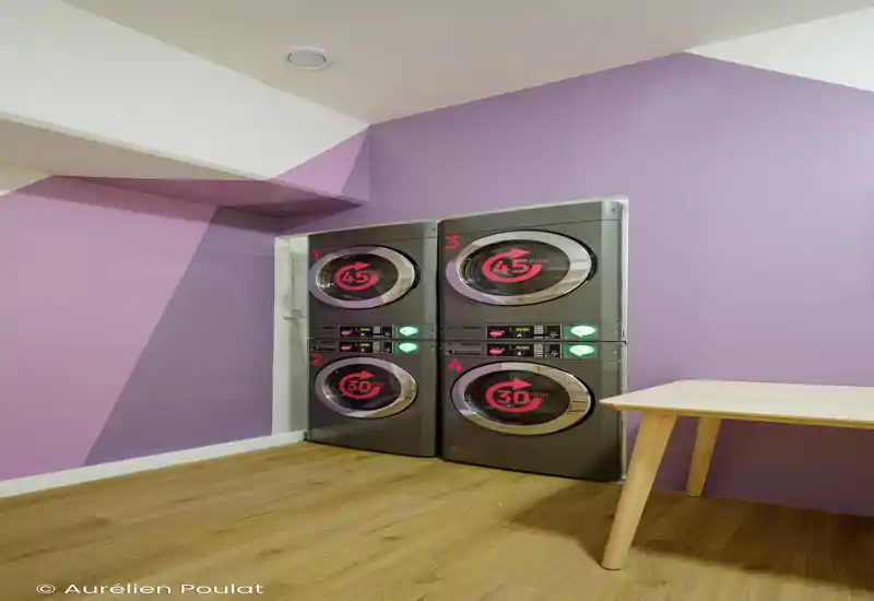 Foto muy corrupta que muestra una zona de dormitorio con una base de cama o plataforma baja y suelo de madera; los artefactos digitales hacen que los detalles no sean fiables.