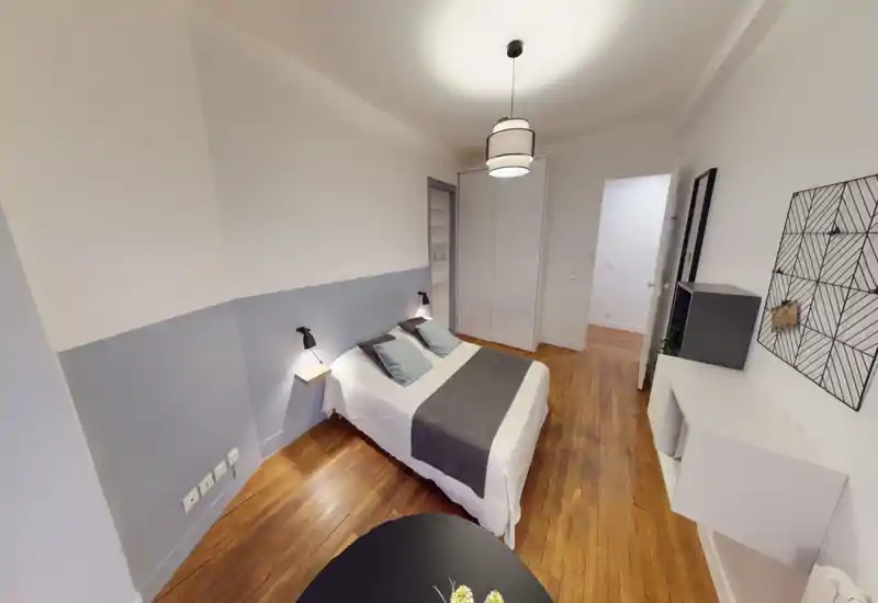 Camera da letto luminosa e ben curata con letto matrimoniale, lenzuola morbide e lampade da comodino; pavimento in legno caldo e armadio incassato per un'atmosfera moderna e rilassante.