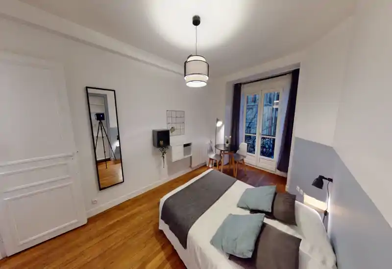 Camera da letto moderna e luminosa con un comodo letto matrimoniale, biancheria morbida e cuscini decorativi. Ampia finestra con balcone che offre luce naturale e un tavolino per la colazione vicino alla finestra.