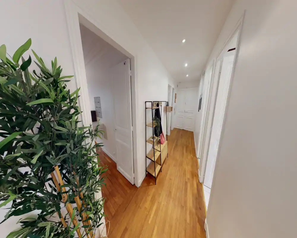 Entrée lumineuse et bien aménagée avec parquet, spots encastrés au plafond et étagère/porte-manteaux — une première impression accueillante.