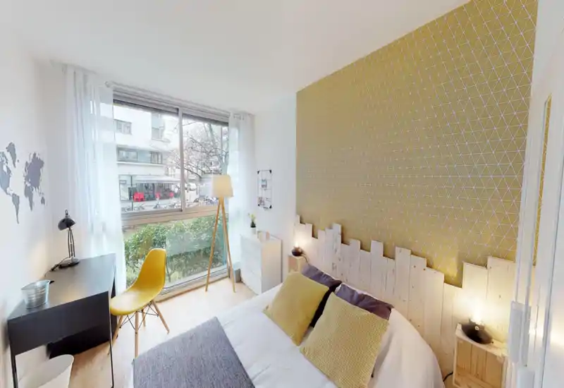 Bright, modern bedroom with a patterned accent wall, wooden headboard and cozy pillows; large window provides ample natural light and a small workspace by the window.