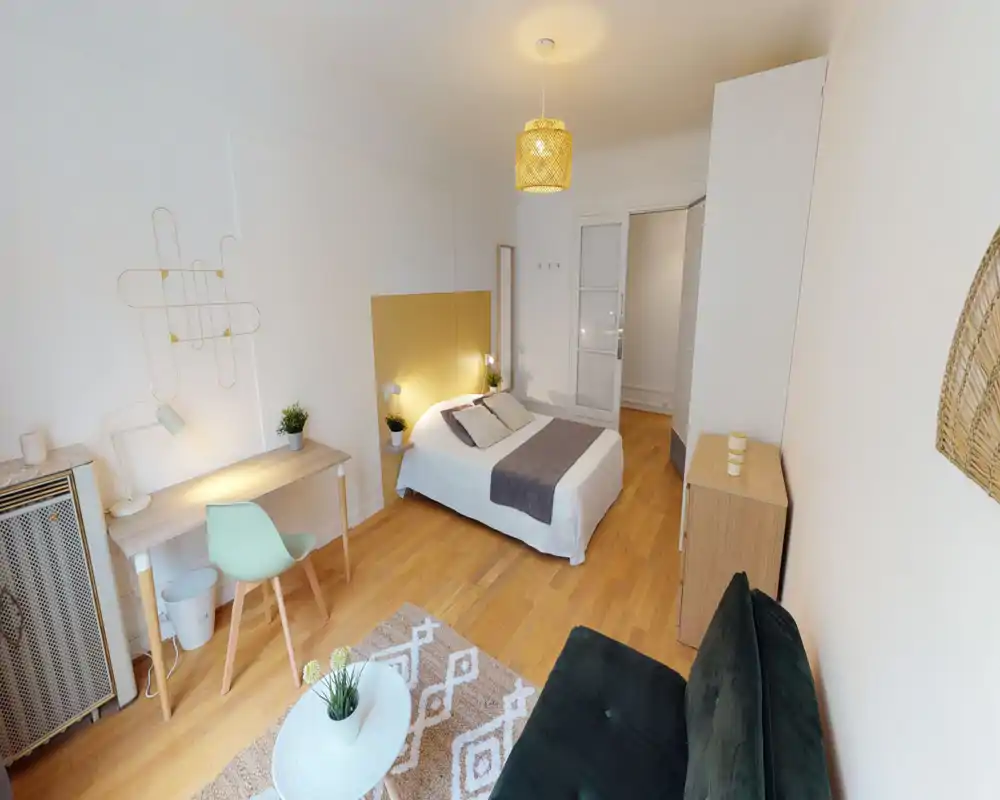 Bright, modern bedroom with a centrally placed double bed, simple desk, cozy textiles and warm wooden floors — well styled for a rental listing.