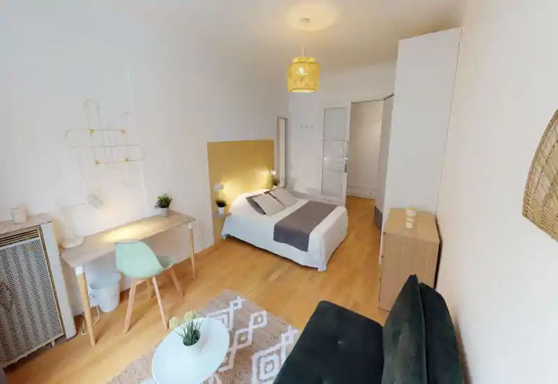 Bright, modern bedroom with a centrally placed double bed, simple desk, cozy textiles and warm wooden floors — well styled for a rental listing.