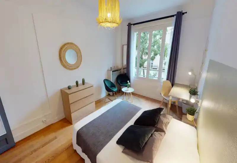 Chambre lumineuse et élégante avec un grand lit double, textiles doux et parquet en bois. Coin salon près de la fenêtre et petit bureau pour se détendre ou travailler.