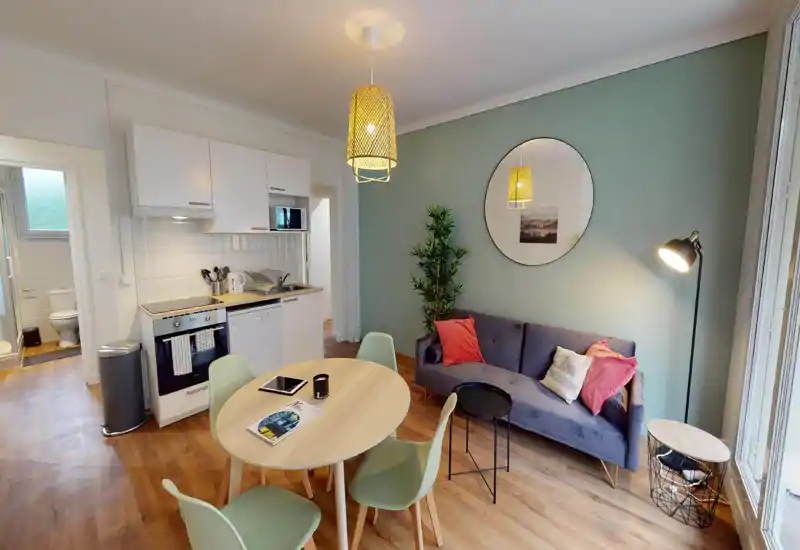 Bright, modern living area with sofa and colorful cushions, a coffee table and wall decor — ideal for relaxed socializing. Note: photo has digital artifacts but room elements remain identifiable.