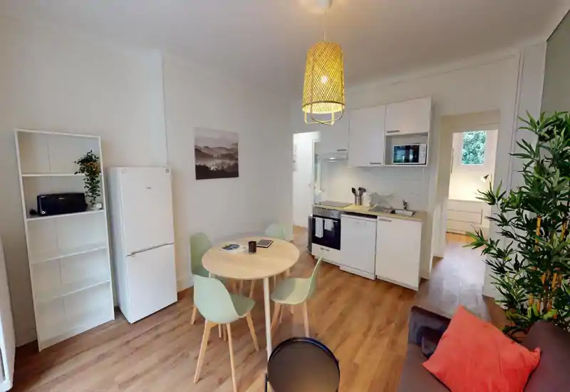 Small dining area with a round wooden table and chairs set in a bright, modern space; image is heavily distorted but the table and seating remain visible.