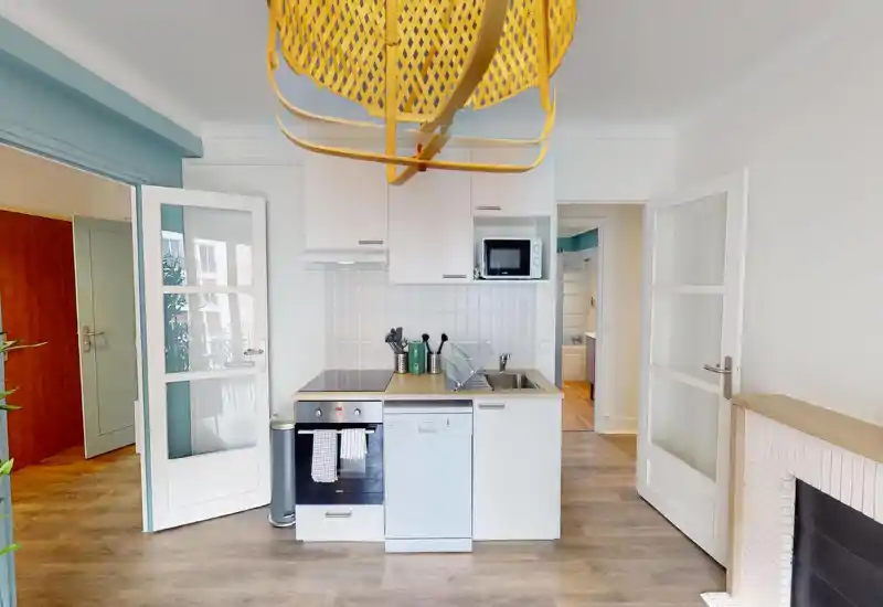 Cucina moderna compatta con mobili bianchi, piano cottura elettrico, lavastoviglie e lavello — luminosa, ordinata e ben curata per un piccolo appartamento.