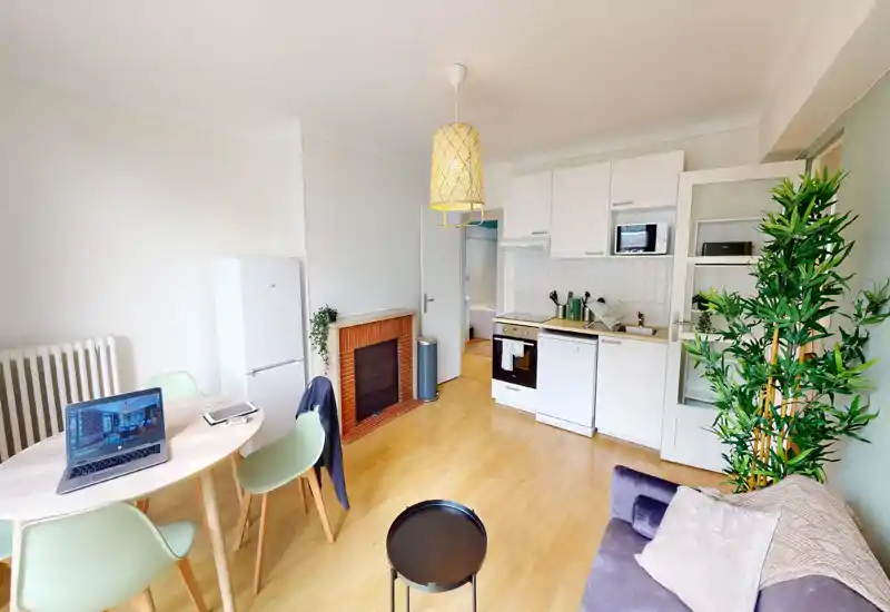 Espace de vie lumineux et moderne avec kitchenette ouverte, petite table à manger et canapé confortable — idéal pour un appartement urbain compact.