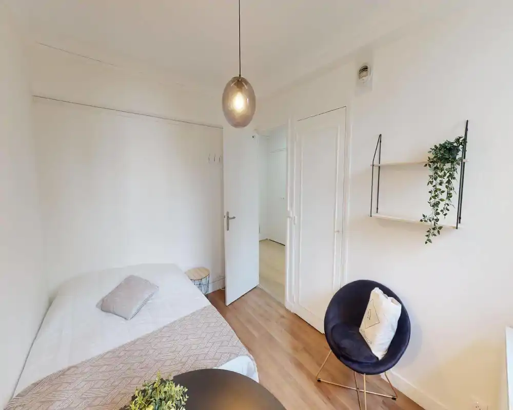 Camera da letto luminosa e bianca con tessili sul letto e piante sospese a parete; l'immagine è fortemente corrotta ma mostra l'area del letto e un arredo neutro.