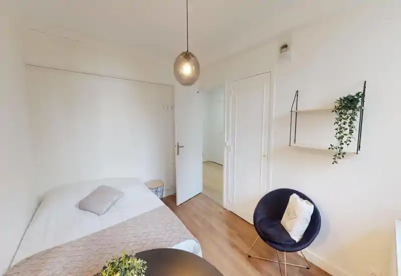 Camera da letto luminosa e bianca con tessili sul letto e piante sospese a parete; l'immagine è fortemente corrotta ma mostra l'area del letto e un arredo neutro.