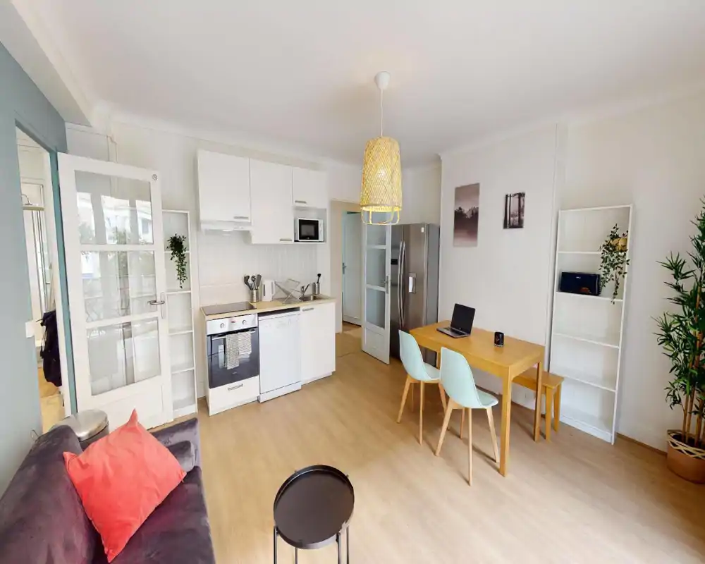 Bright, modern open-plan living area with a small fitted kitchen, wooden dining table and a comfortable sofa — ideal for city stays.
