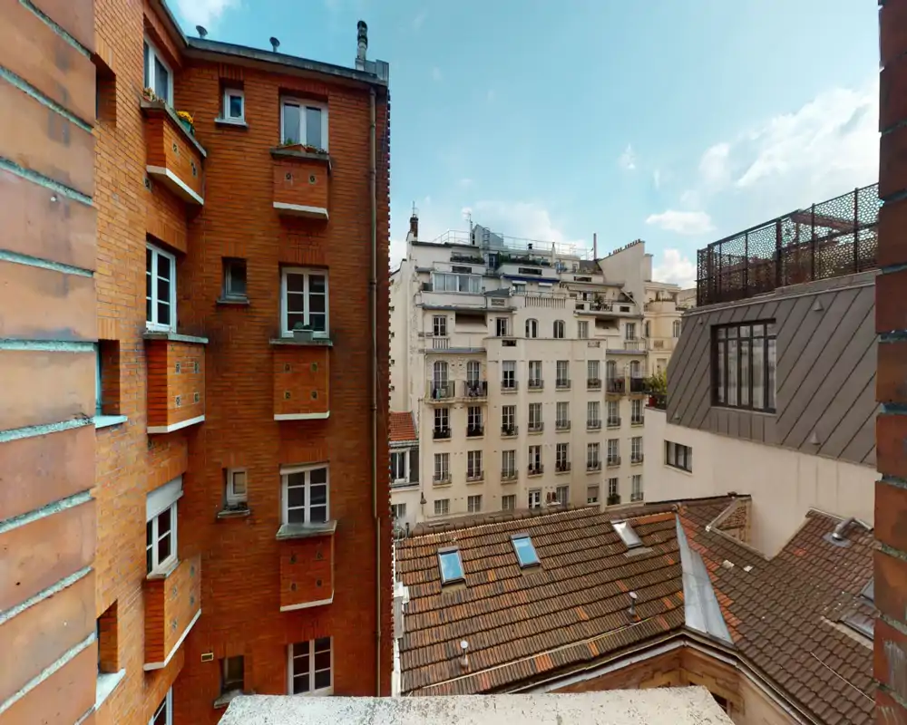 Vista urbana sui tetti che mostra edifici in mattoni e intonaco, tegole in cotto e un cielo luminoso — ideale per valorizzare un balcone o una finestra esposti al sole.