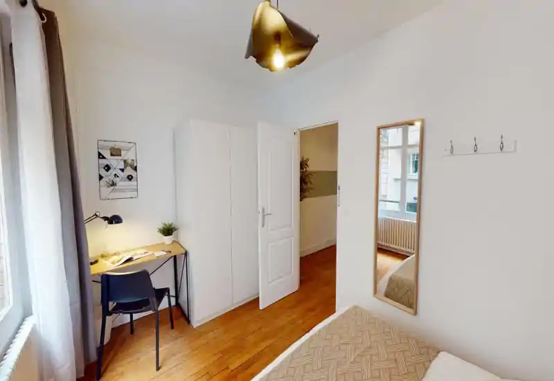 Chambre claire avec lits visibles et décor moderne simple; l'image présente des artefacts numériques mais montre matelas, oreillers et éléments près du lit exploitables pour une annonce.