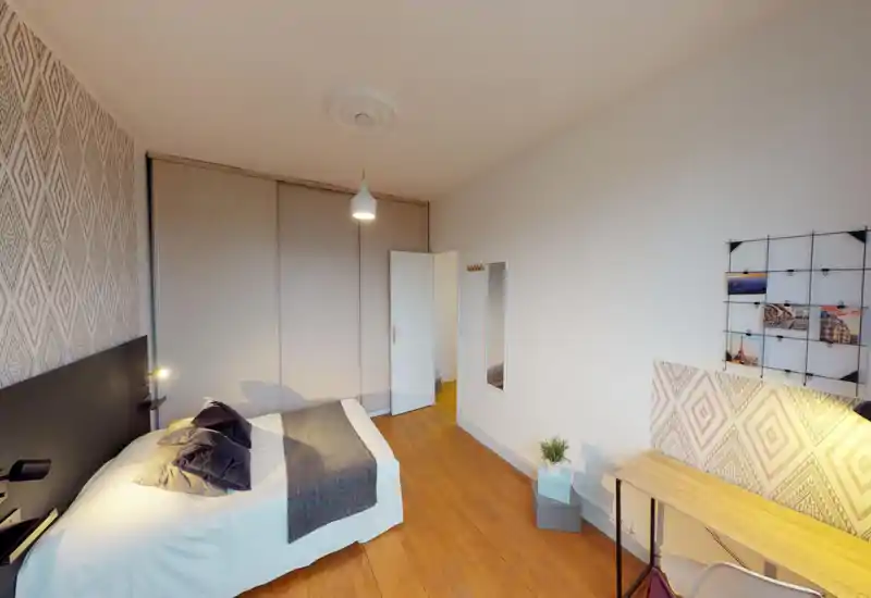 Chambre lumineuse et élégante avec un lit double confortable, des textiles doux et une décoration coordonnée ; sol en bois et petit bureau pour un espace chaleureux et fonctionnel.